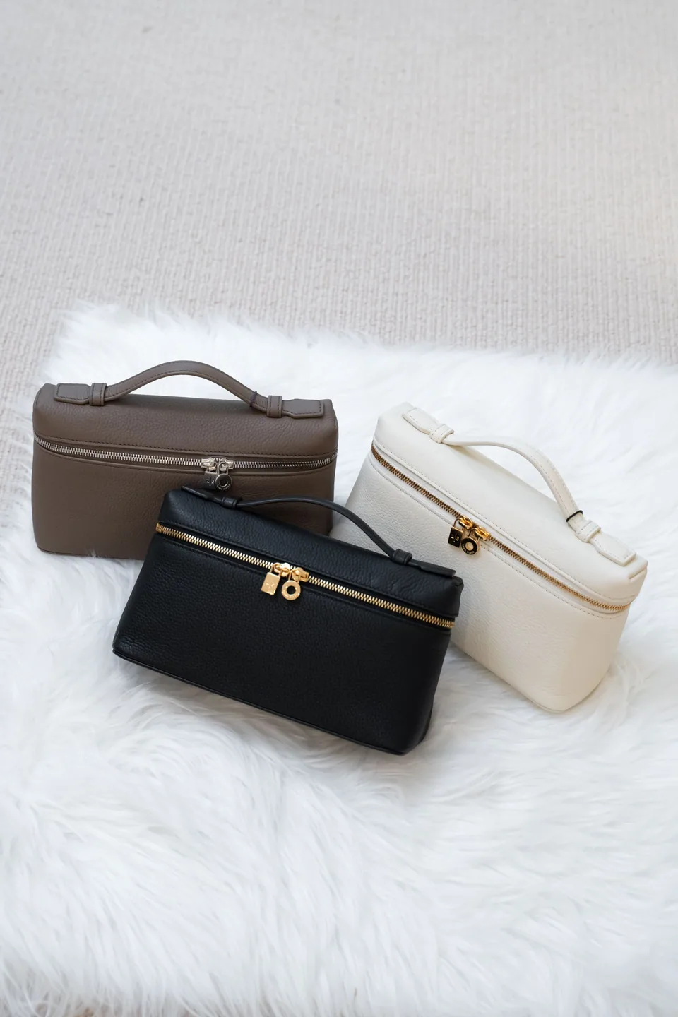 A selection of compact leather bags on a soft white surface