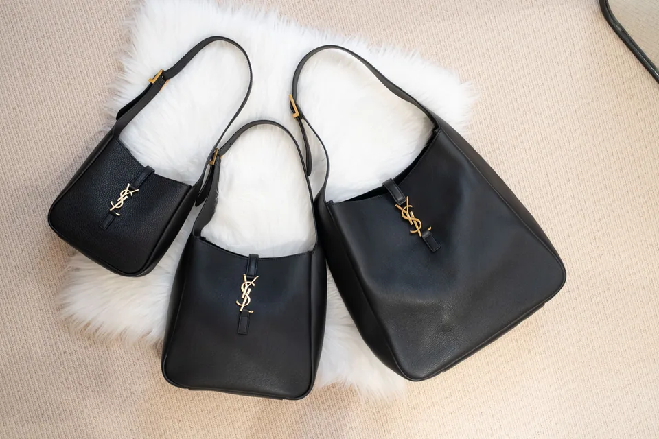 Several black designer handbags presented together
